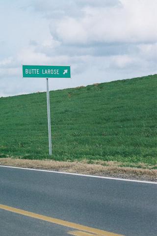 a sign near a road with green grass on the side