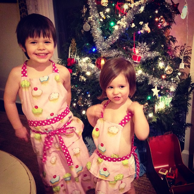 two children wearing matching clothing in front of a christmas tree