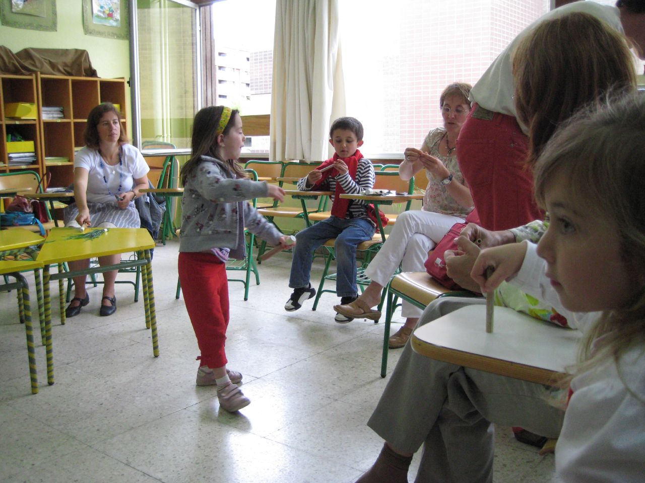 two little girls sitting in chairs next to children playing