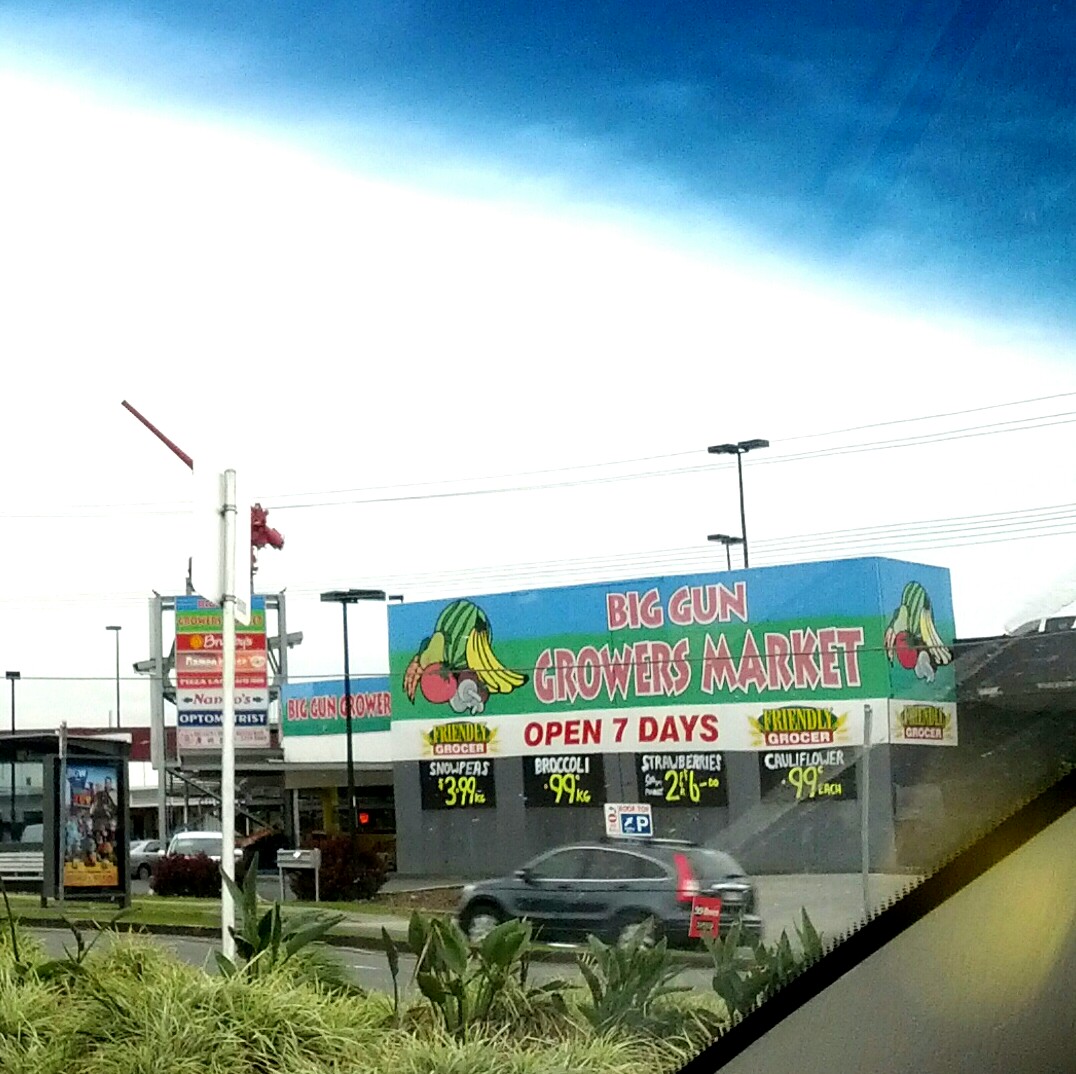 a grocery store with cars and other vehicles in the foreground