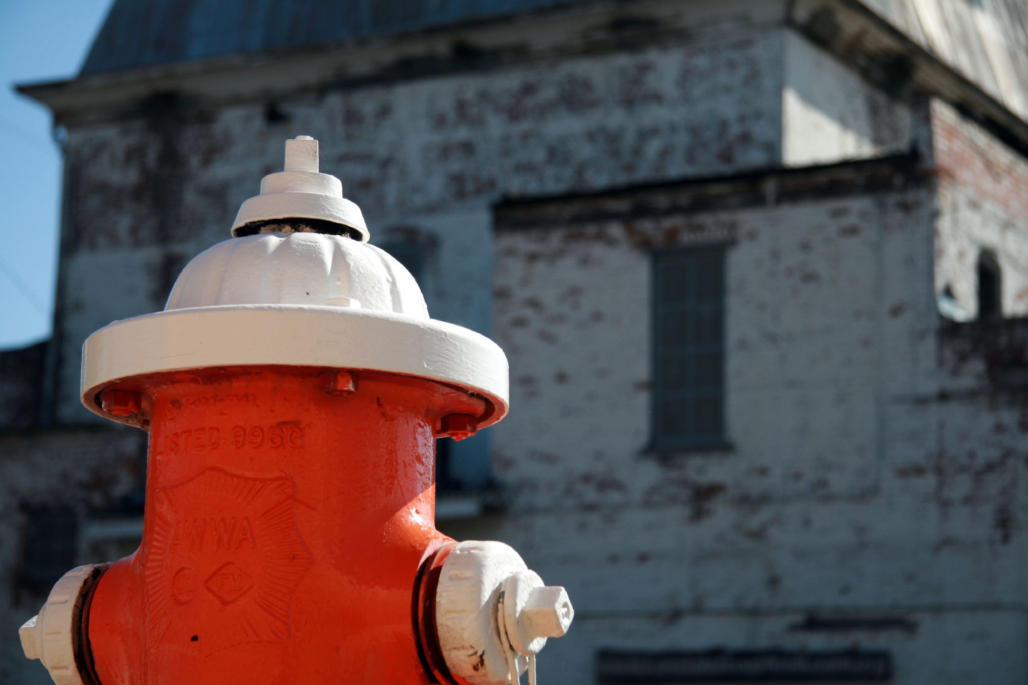 an orange and white fire hydrant in front of an old building