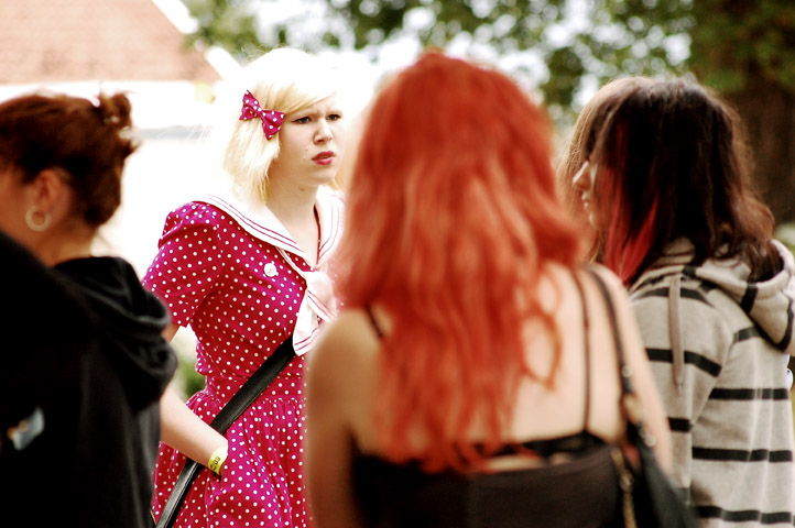woman dressed in pink polka dot dress with other women looking around