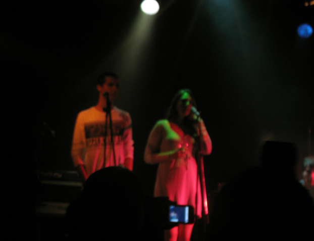 two people in concert holding microphones and talking