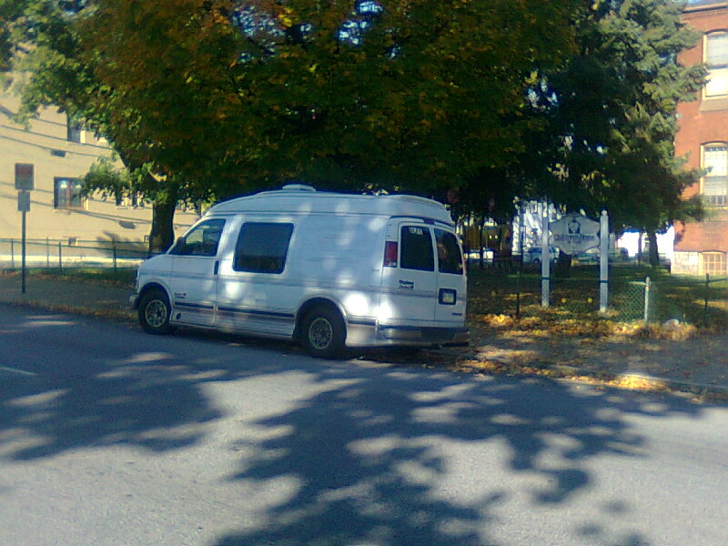 a white van parked on the side of a road next to trees