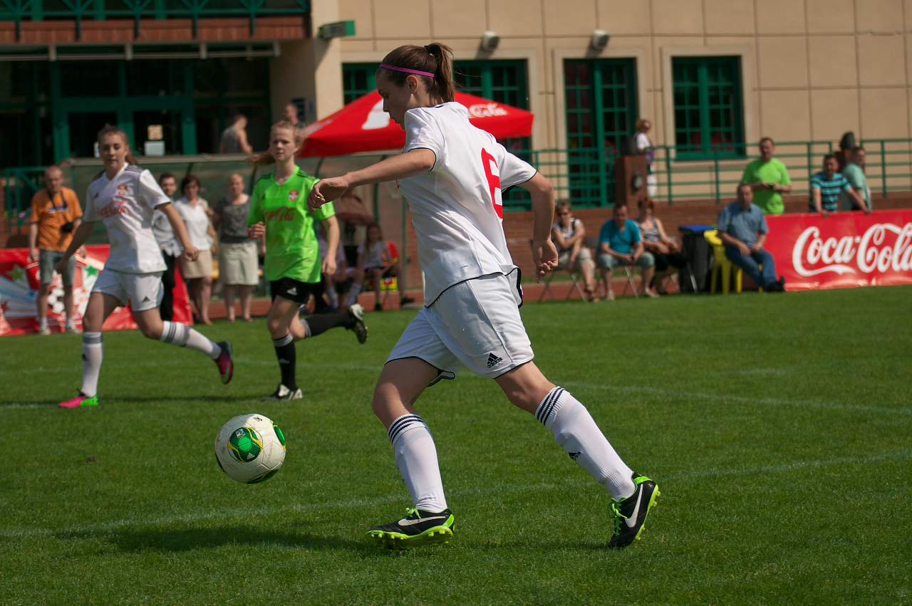 soccer player in white jersey dribbles a ball around green field