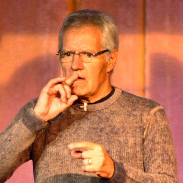 a man with glasses on is pointing his finger at the camera
