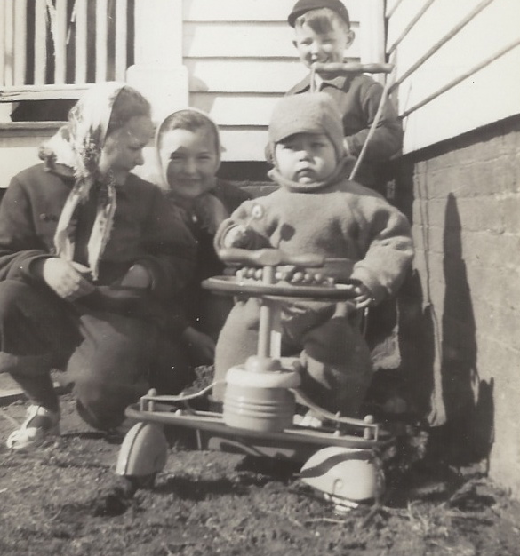 three children sitting together on a small cart