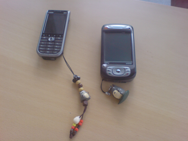 two cellphones are on a table with a beaded necklace