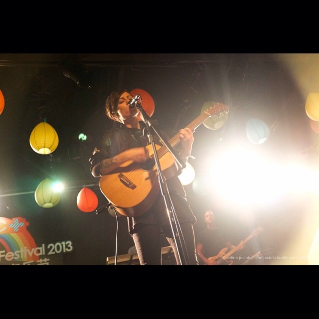 a male with a guitar on stage at night