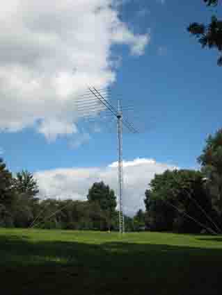 a phone tower and antenna on the side of the grass covered field