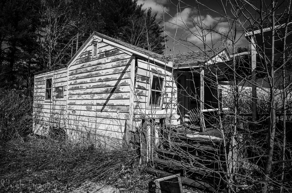 an old shack sits in the grass near some trees