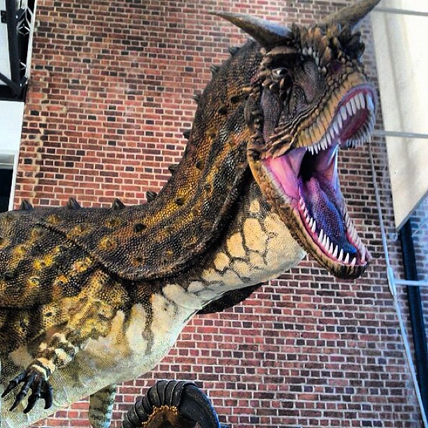 an inflatable dinosaur is on display against a brick wall