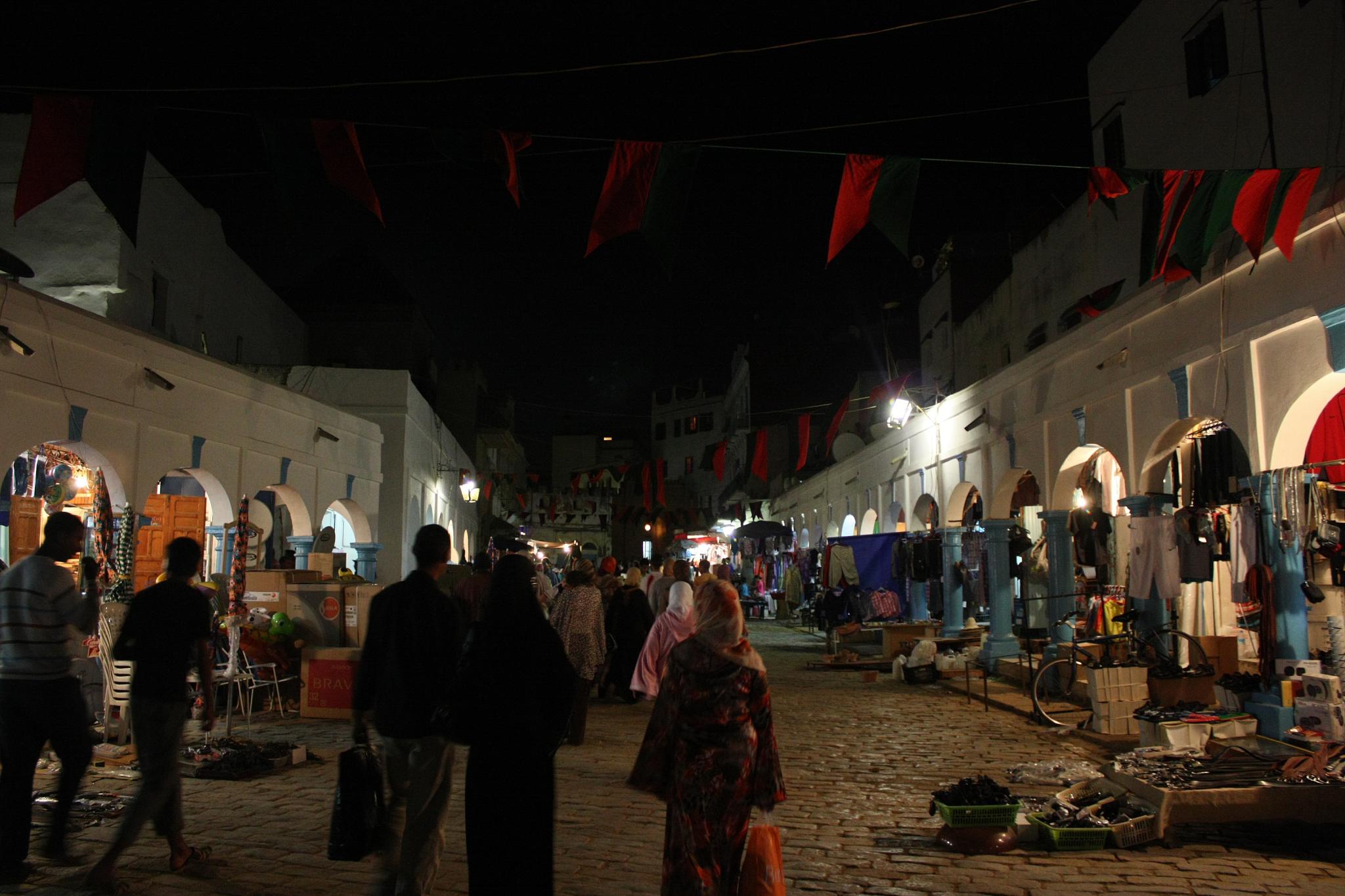 people walking around and looking at a street scene at night