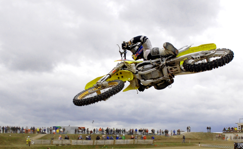 a motorcyclist is airborne with spectators watching