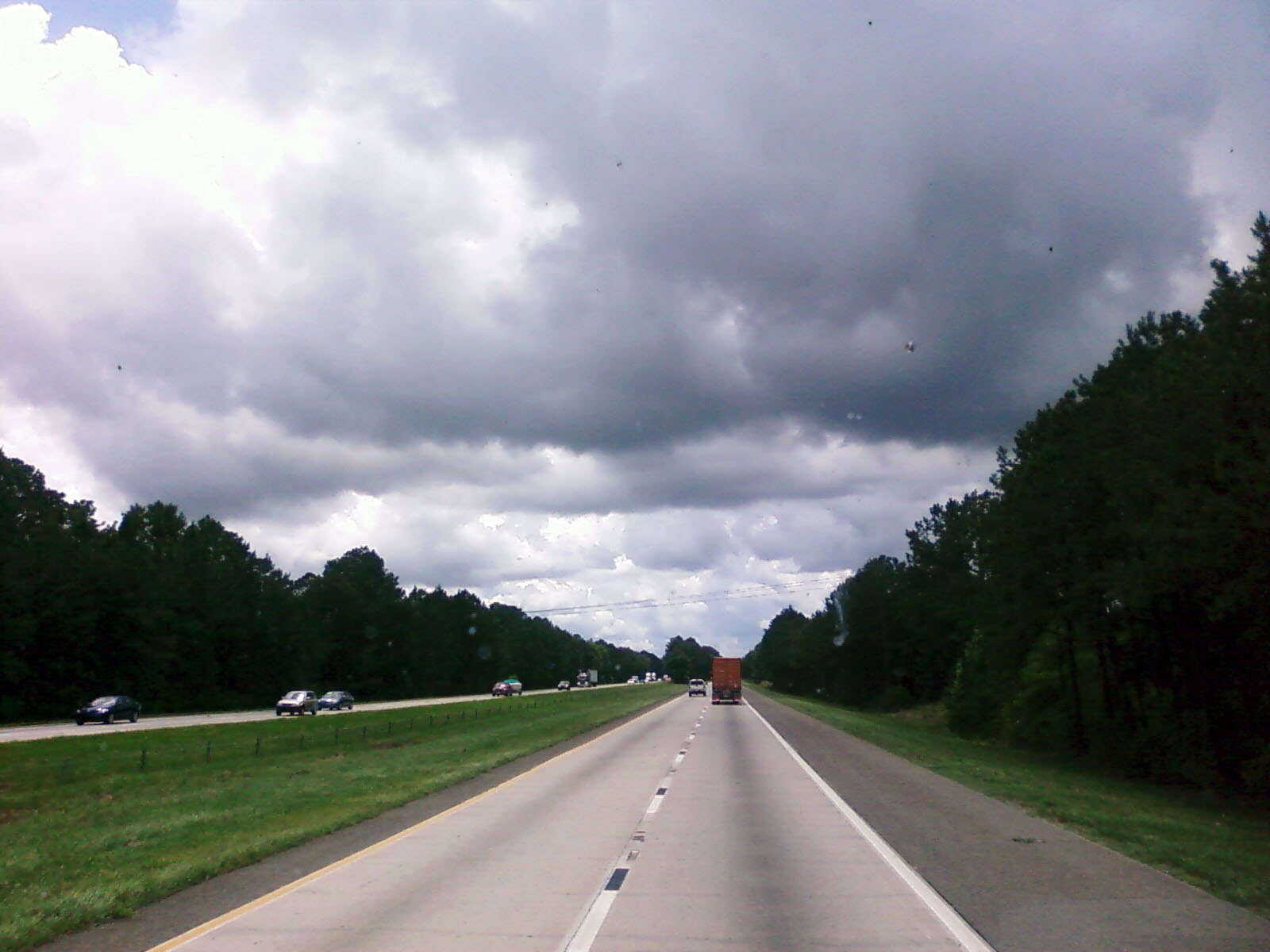 cars on road approaching large grassy area in the distance