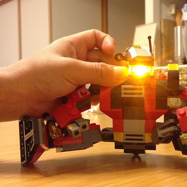 the person is making a small lego toy that's like an adult robot