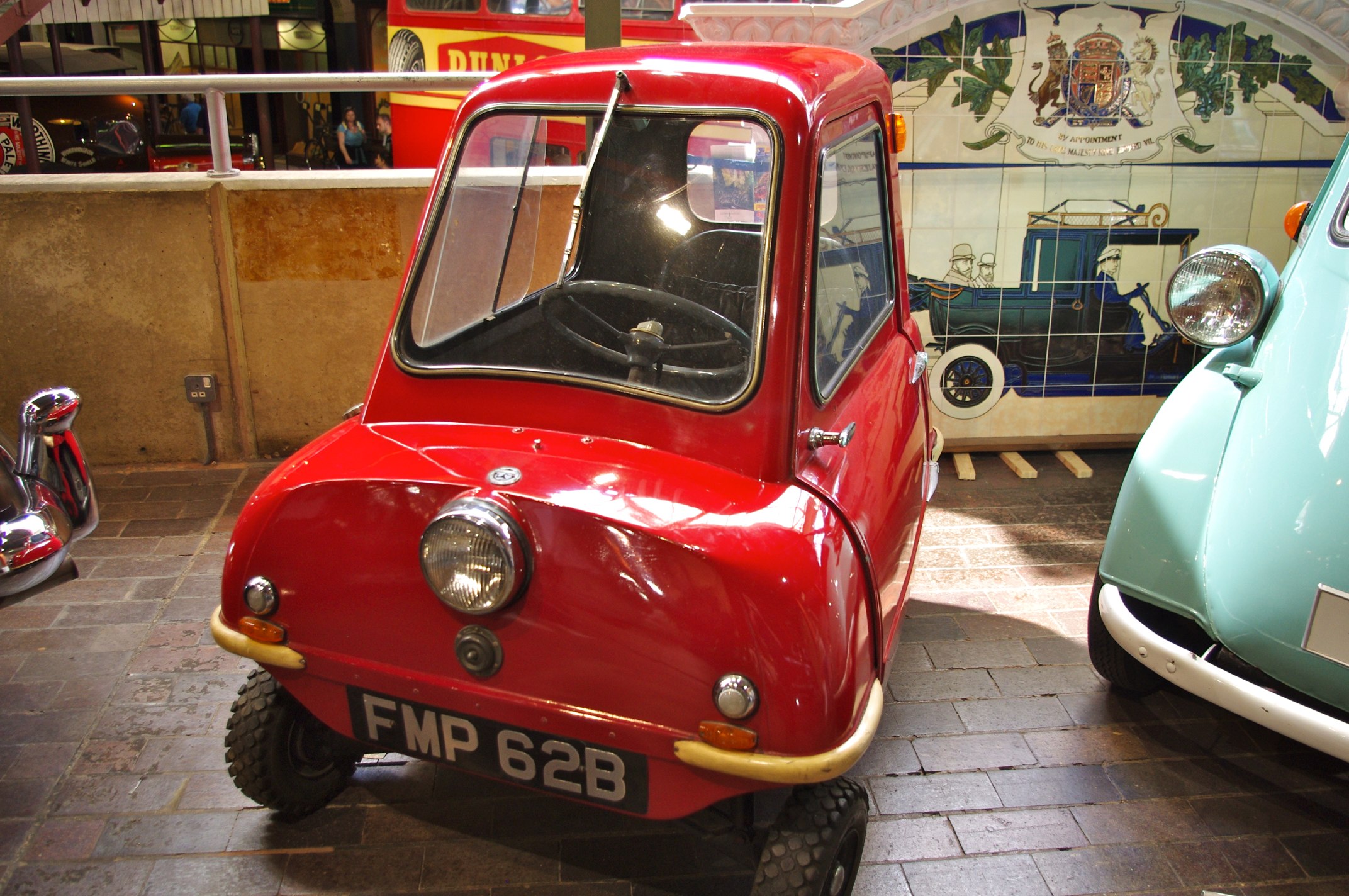 a small, restored car parked inside a museum