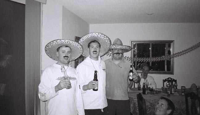 four people are standing and wearing hats, all holding beers