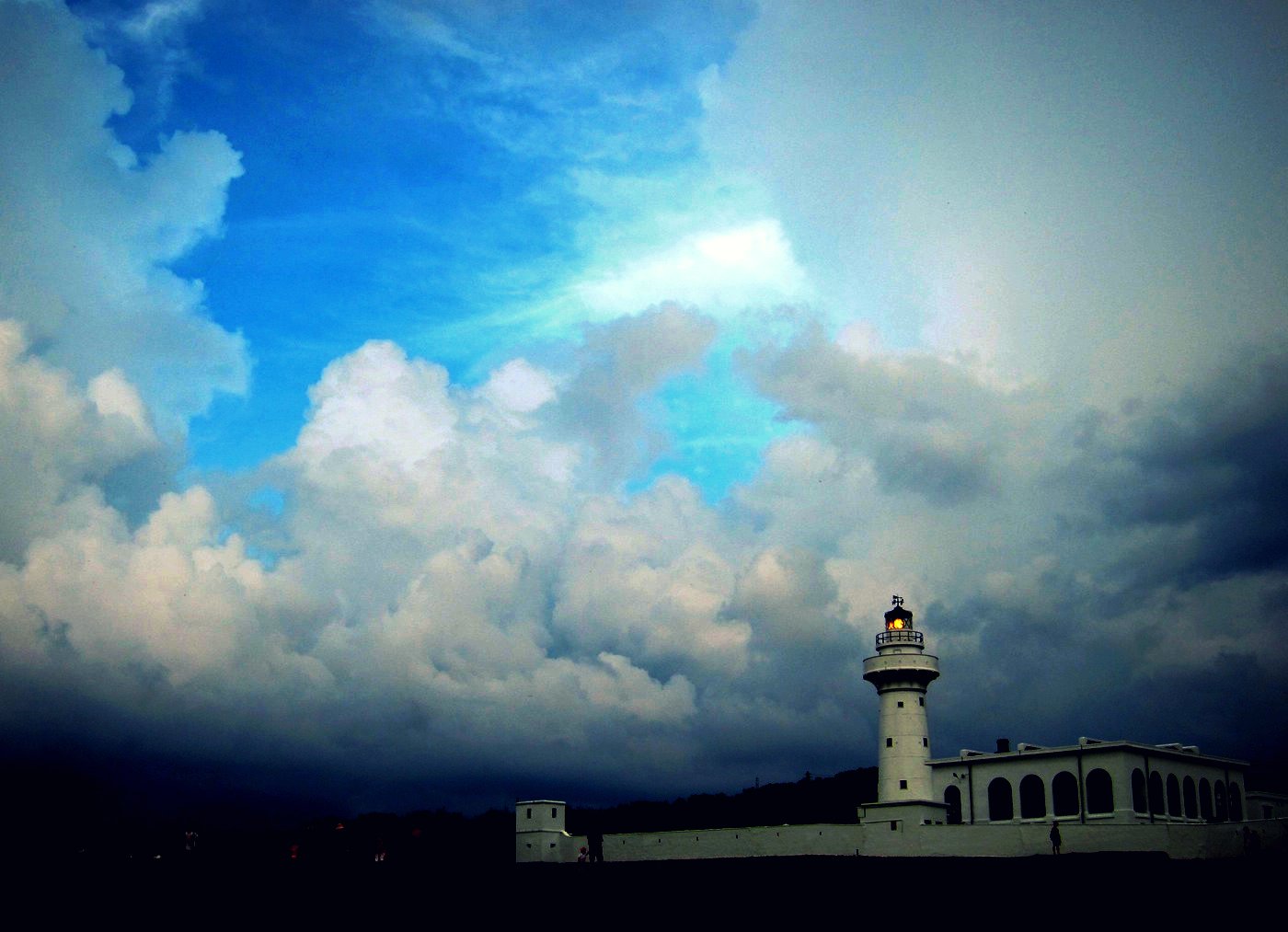 clouds surrounding the white lighthouse on a cloudy day