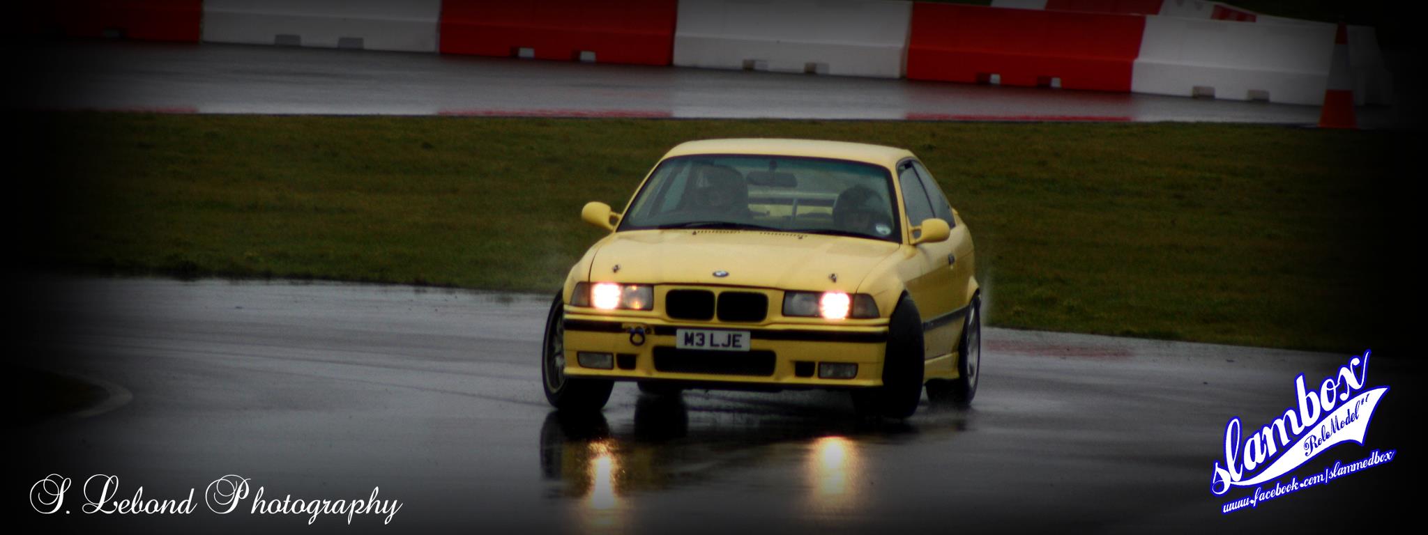 a yellow bmw car racing on a track
