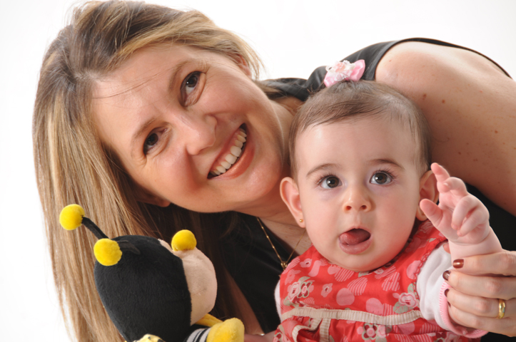 a woman holding a baby with two different birds around her