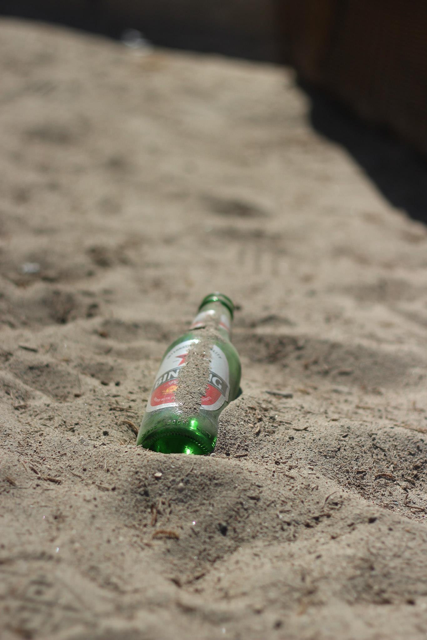 a bottle that is sitting in the sand