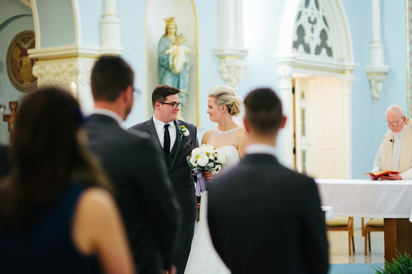 a bride and groom smiling at each other as they walk down the aisle
