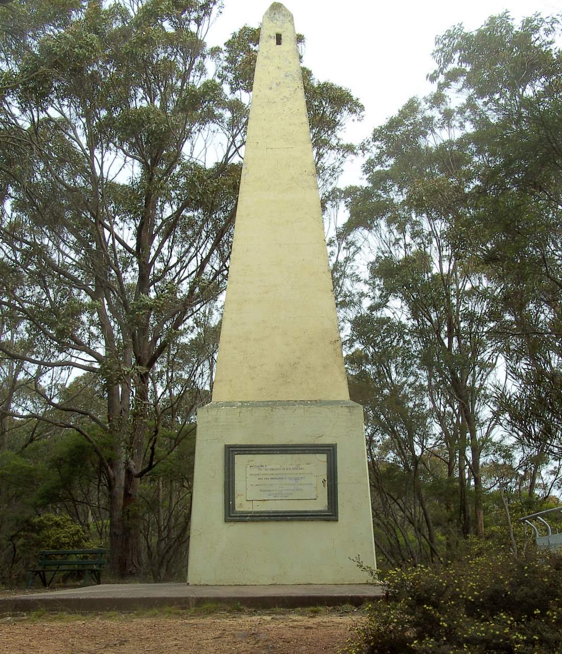 a cement clock tower next to many trees