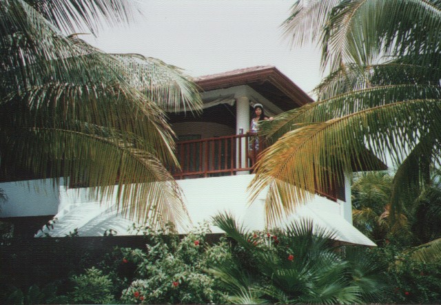 two people look out the upper balcony of a small tropical home