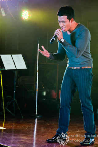 the man in pants sings into his microphone on the stage