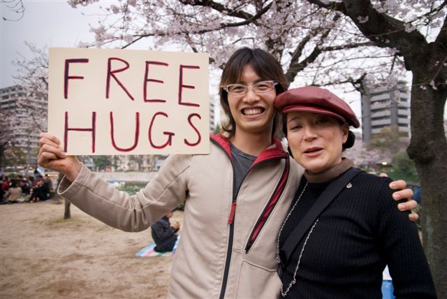 two people holding a sign with a free hugs message
