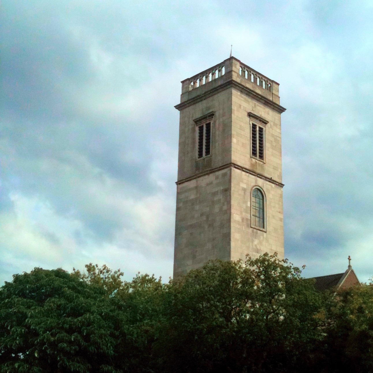 a white stone clock tower towering above trees