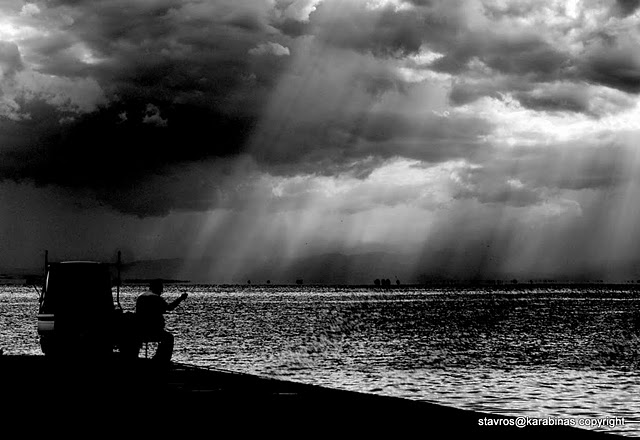 a person on the beach near the water with a truck in front of them under a dramatic sky