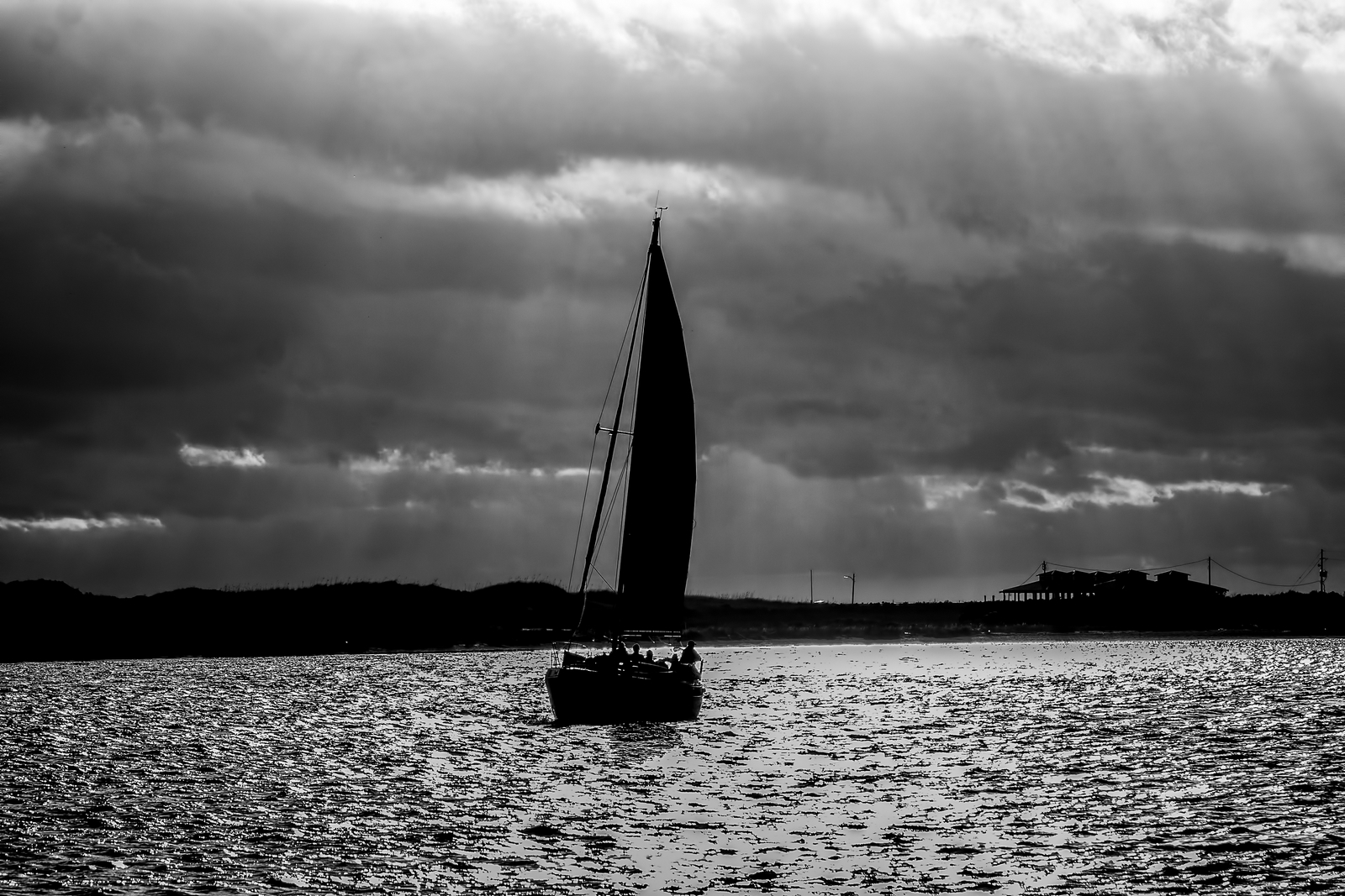 a sail boat in the ocean under a cloudy sky