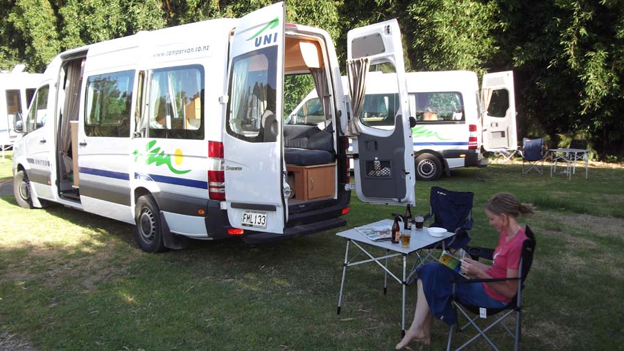 people sitting in chairs next to parked campers