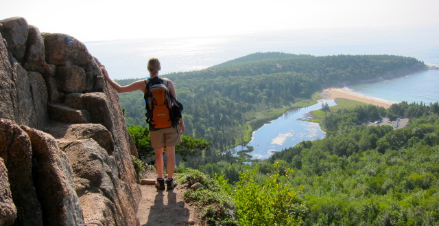 a person standing on the side of a steep cliff next to a body of water