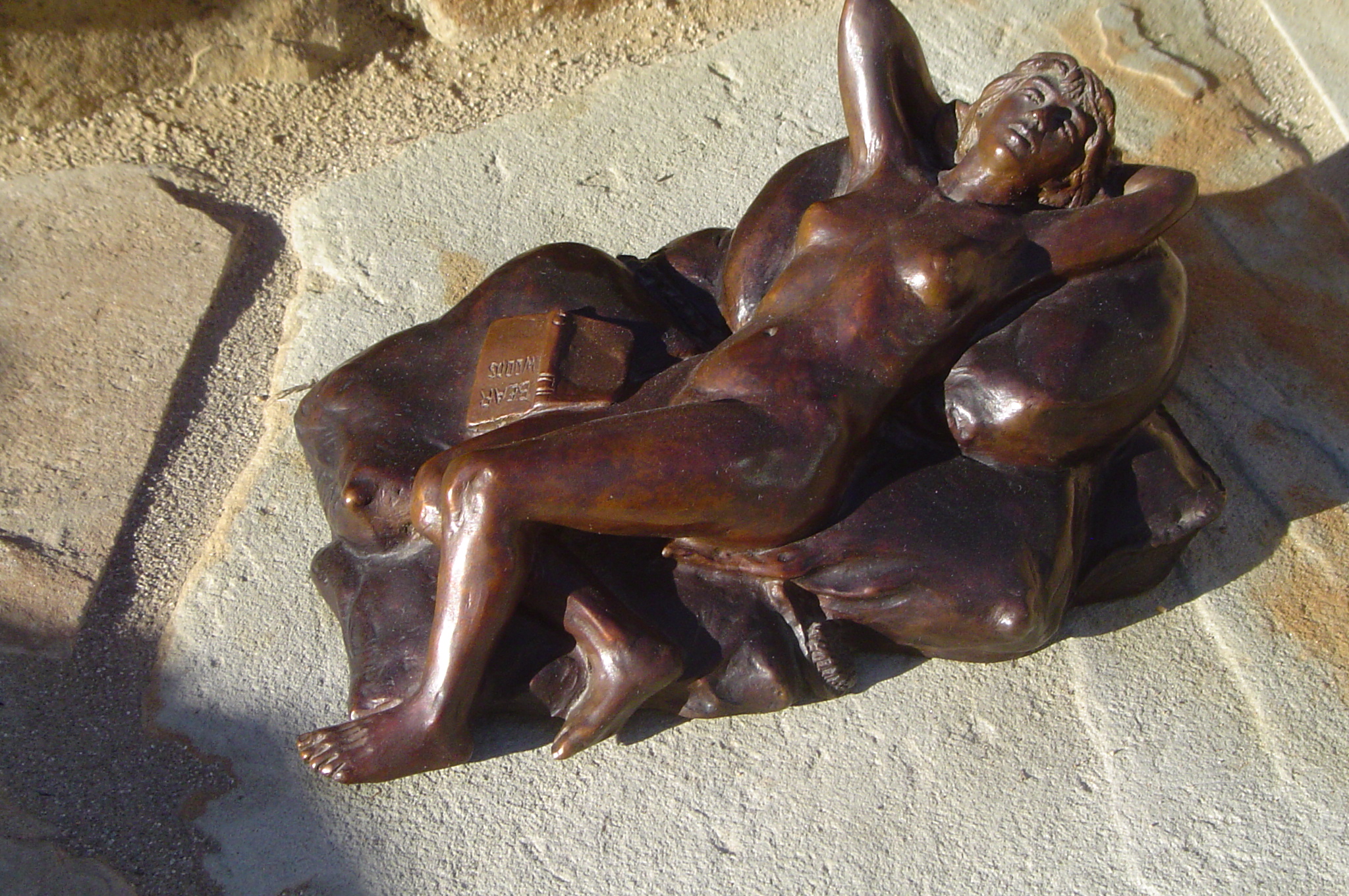 bronze statue depicting two women holding each other and hing them