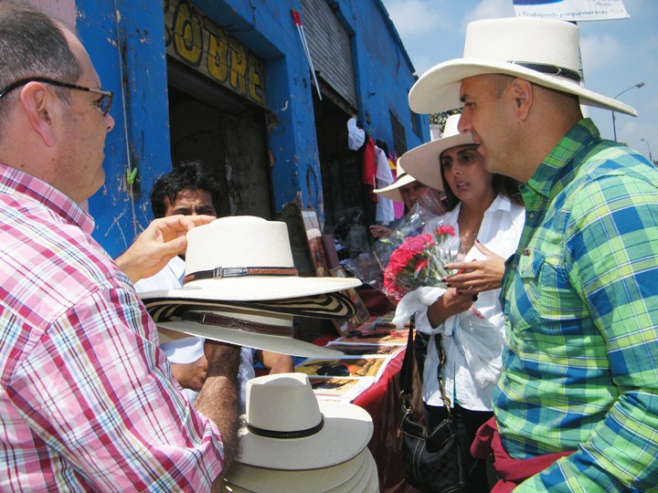 a man is handing flowers to two people near hats