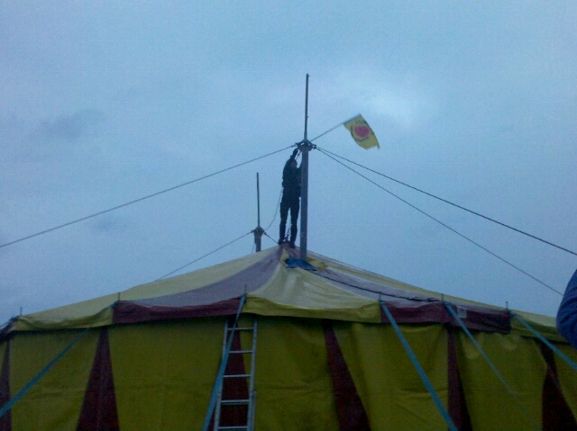 there are people on top of a tent with a flag