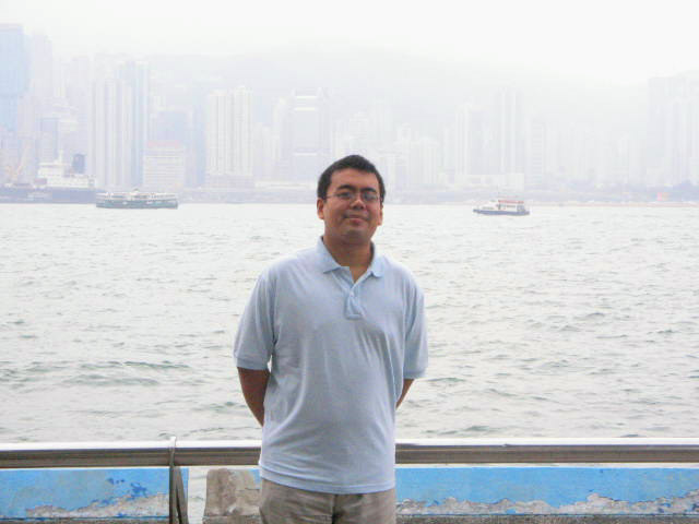 man standing in front of a lake near large cityscape