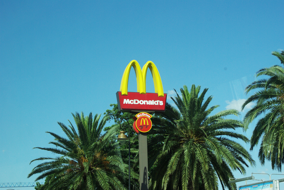 a mcdonald's sign and palm trees in front of it