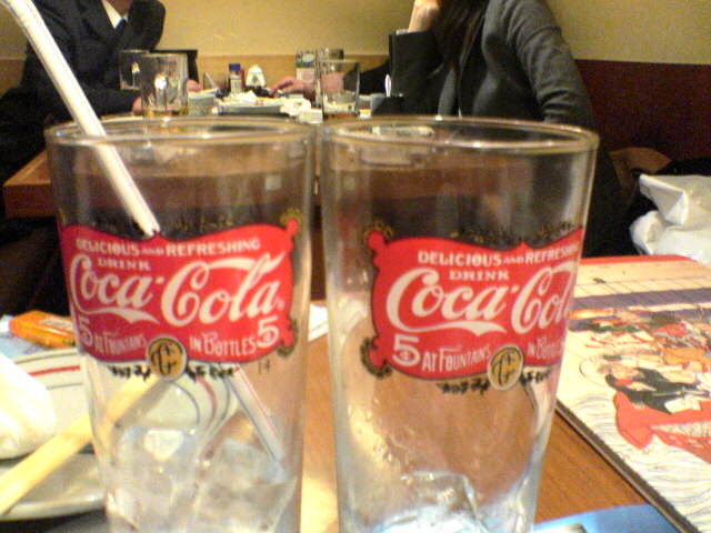 two glasses with coca cola on them are on the table