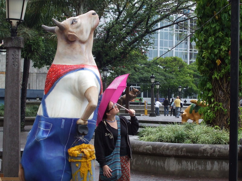 two women stand under the statue of a dog in a raincoat