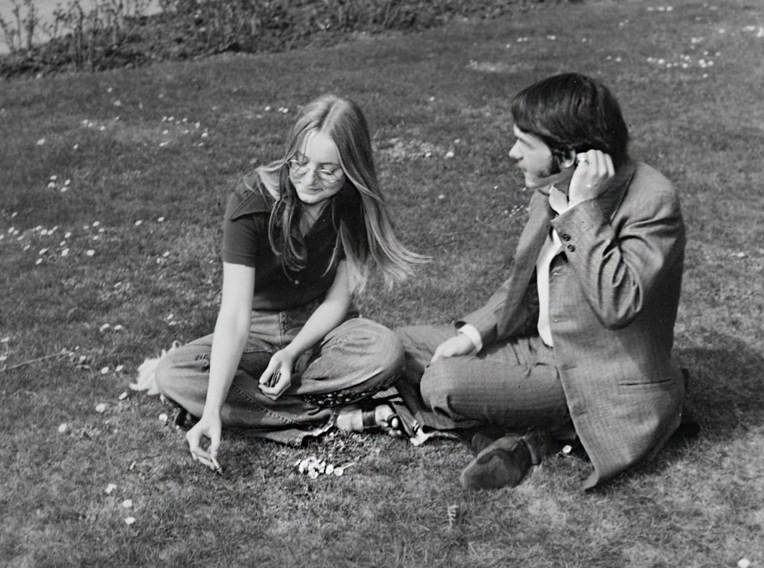 two people that are on the grass with cell phones