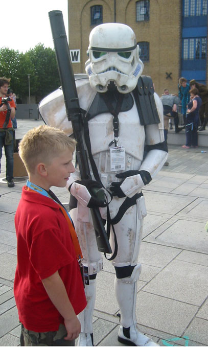 a boy dressed as storm trooper holds on to a lamppost