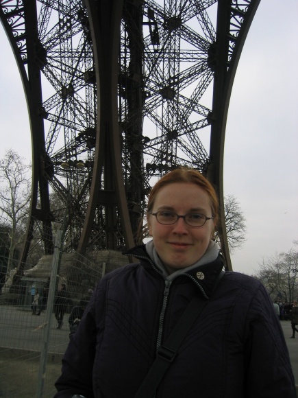 a woman is standing near a structure that appears to be a giant, metal structure