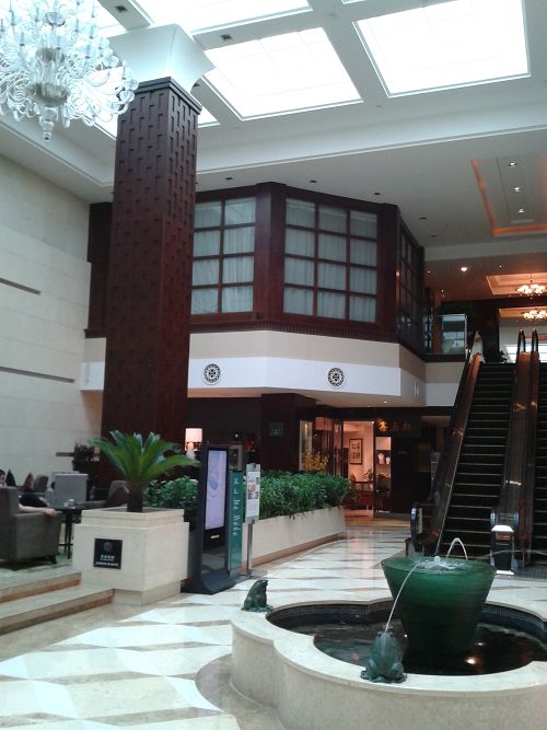 a lobby with an indoor fountain and stairs in the background