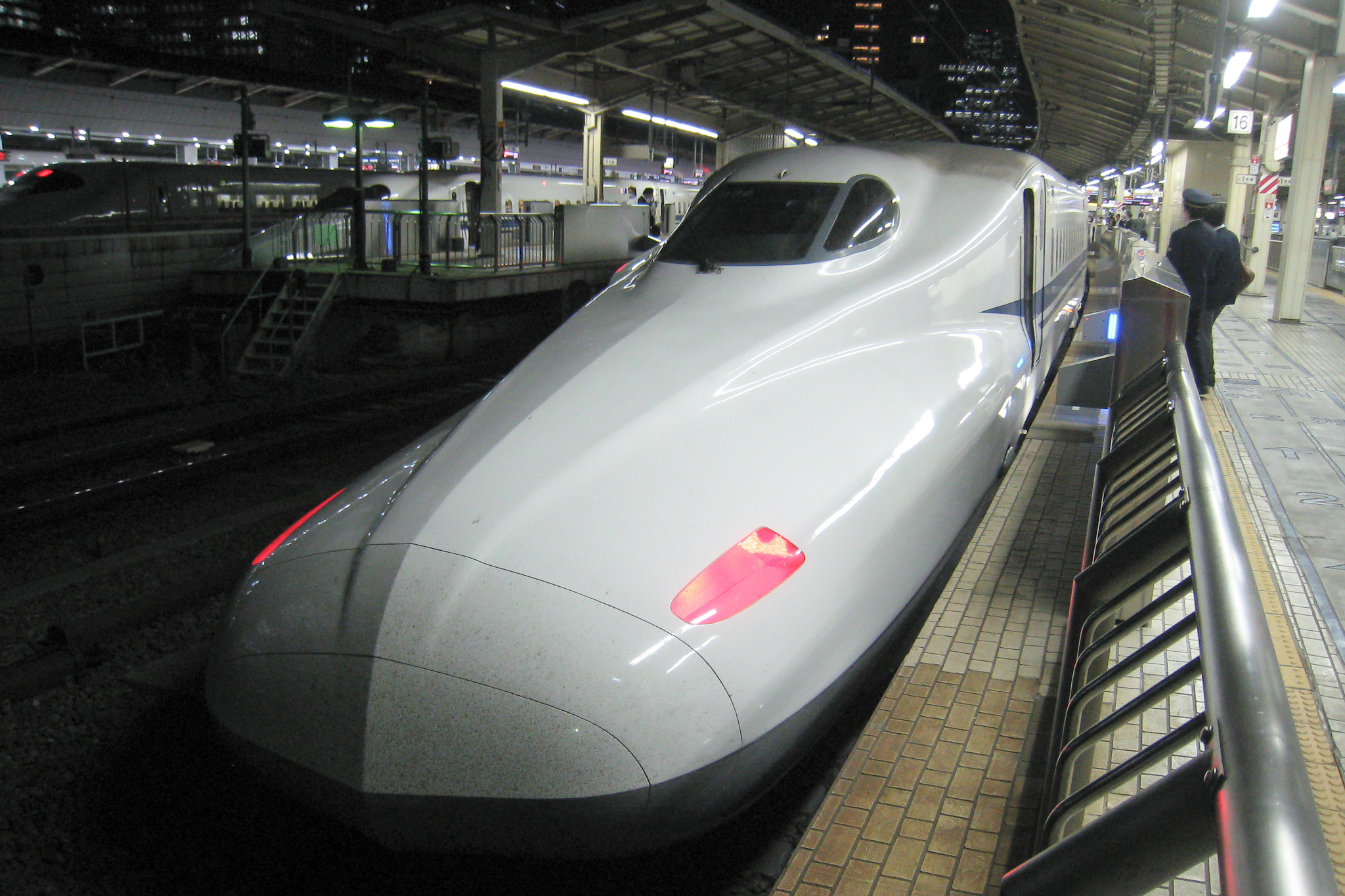 a sleek silver train sits at the platform at night