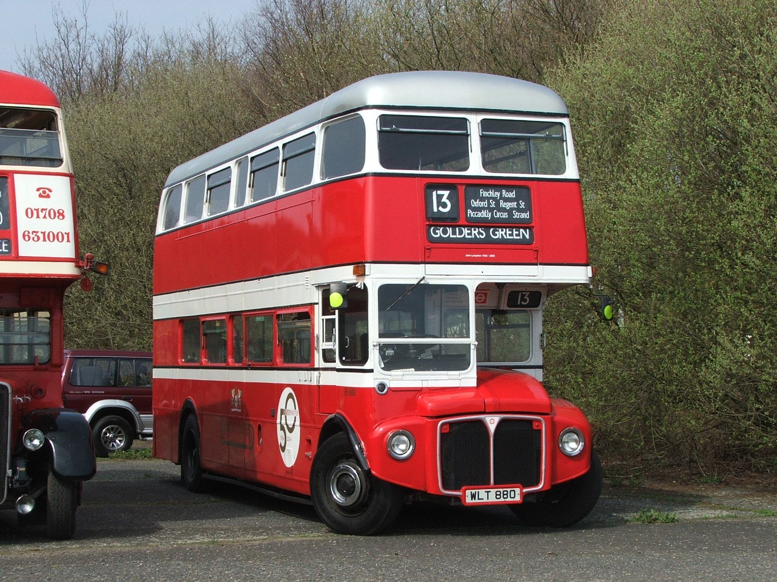 a red two story bus on road next to a car