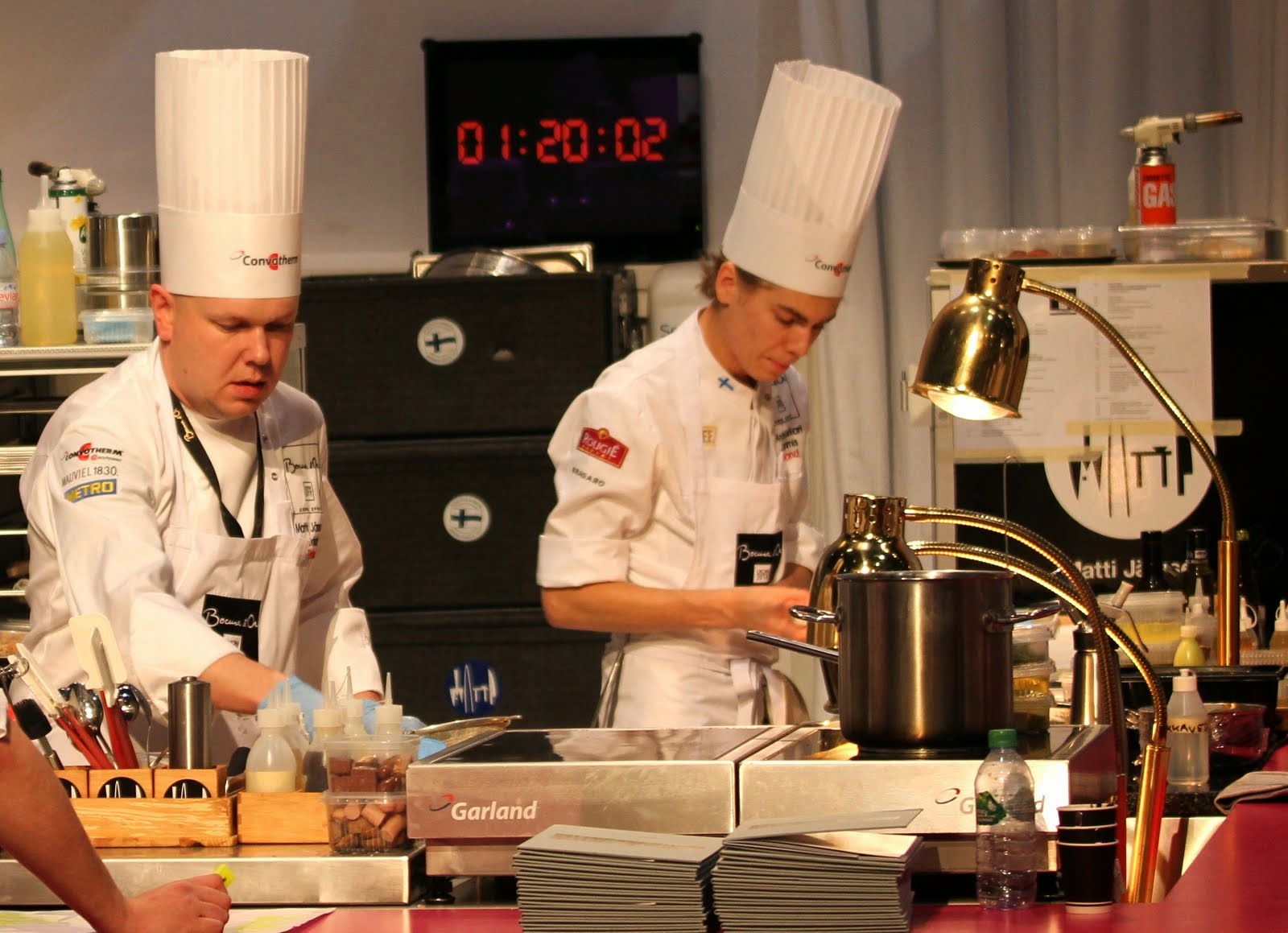 two chefs standing in a kitchen preparing food